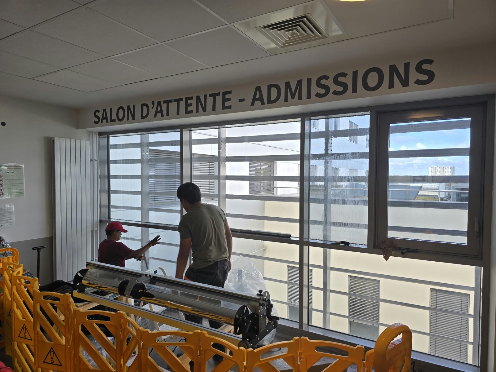 Techniciens DFP France posant le film solaire sur la baie de la salle d'attente des admissions de la Clinique Saint-Jean l'Ermitage à Melun (77)