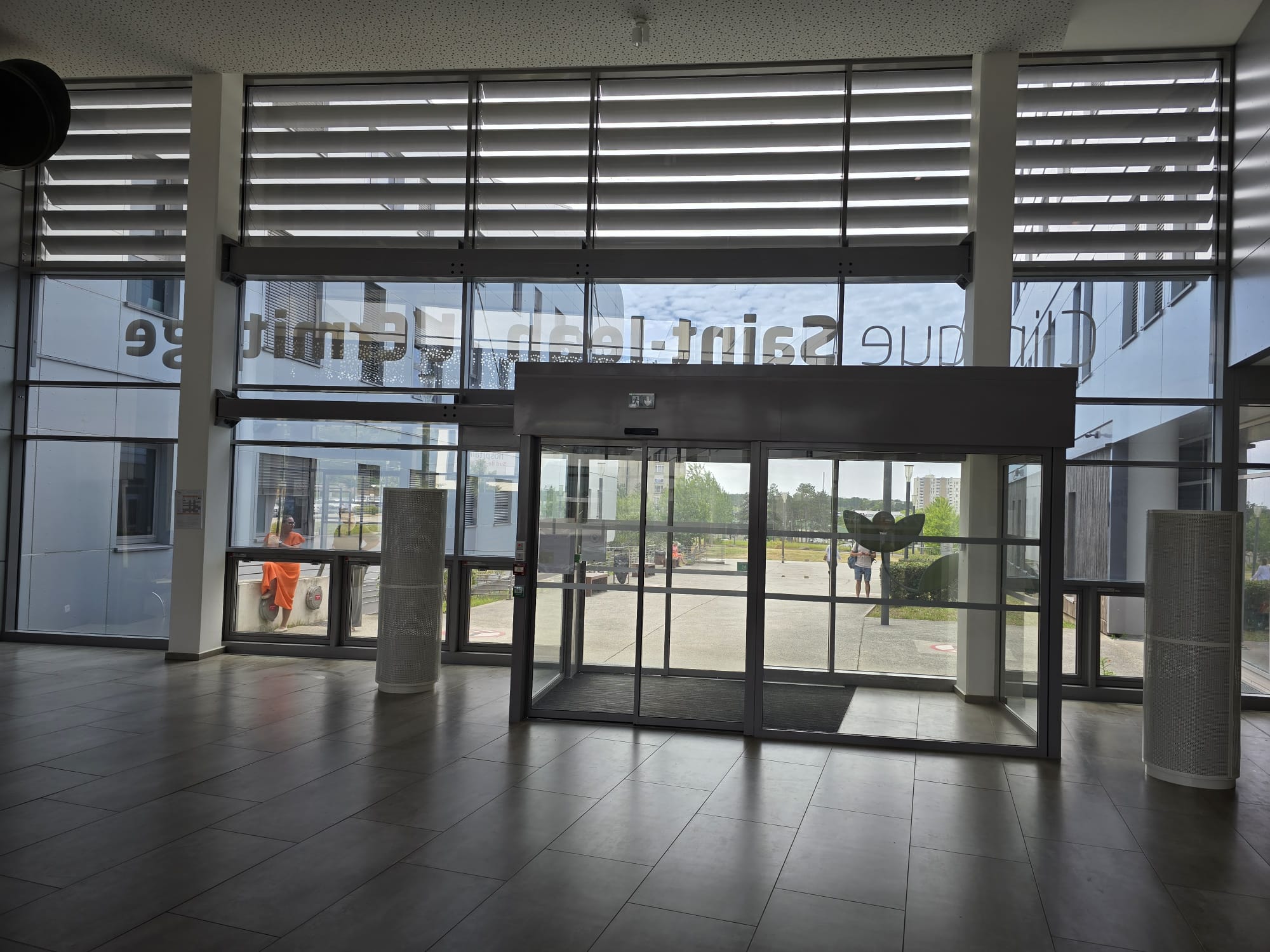Hall d'accueil entièrement vitré de la Clinique Saint-Jean l'Ermitage à Melun après pose du film solaire — lumière naturelle préservée