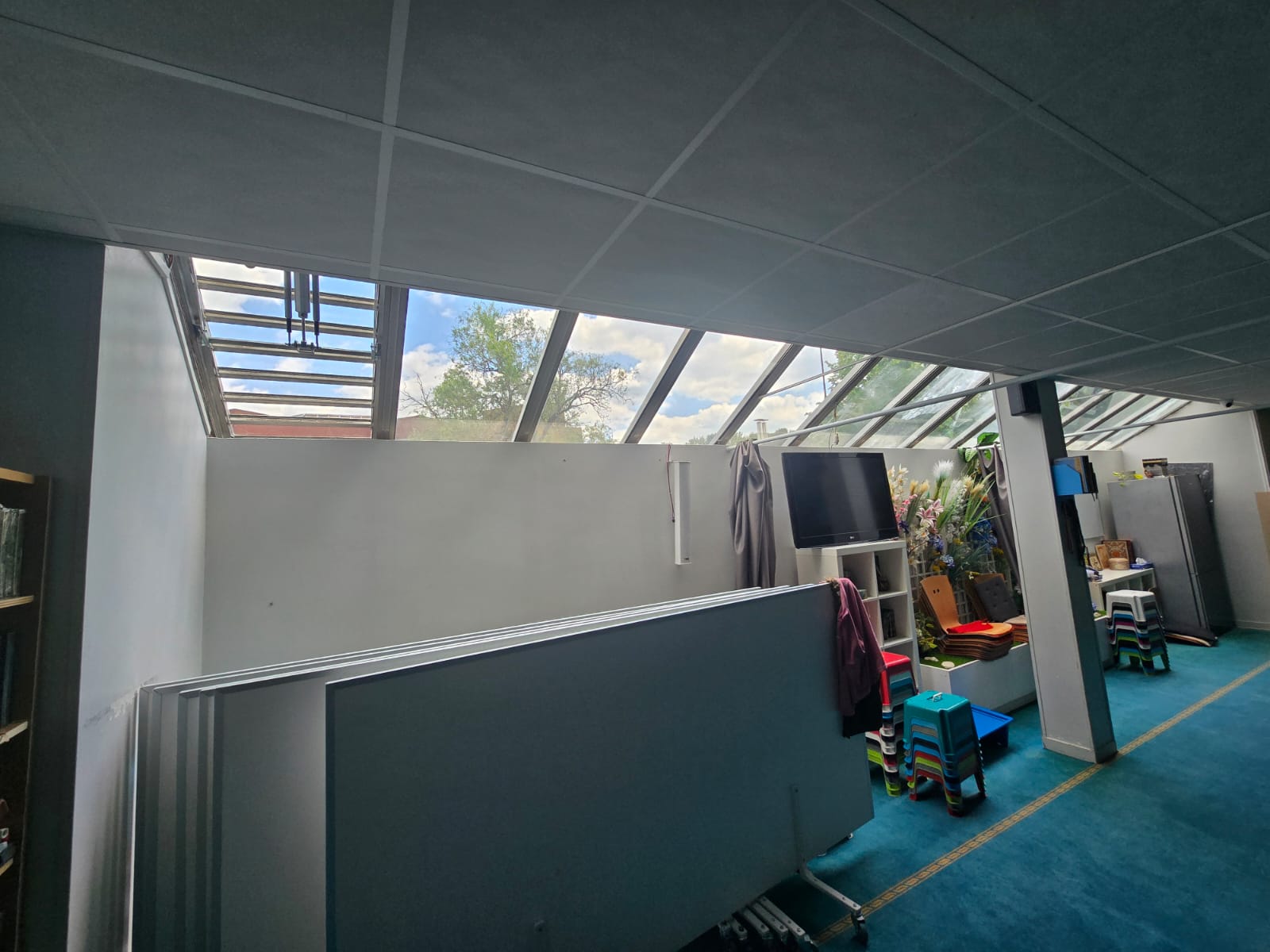 Vue intérieure du studio Solarscène sous la verrière inclinée après pose du film solaire — espace studio avec sols turquoise, lumière naturelle conservée