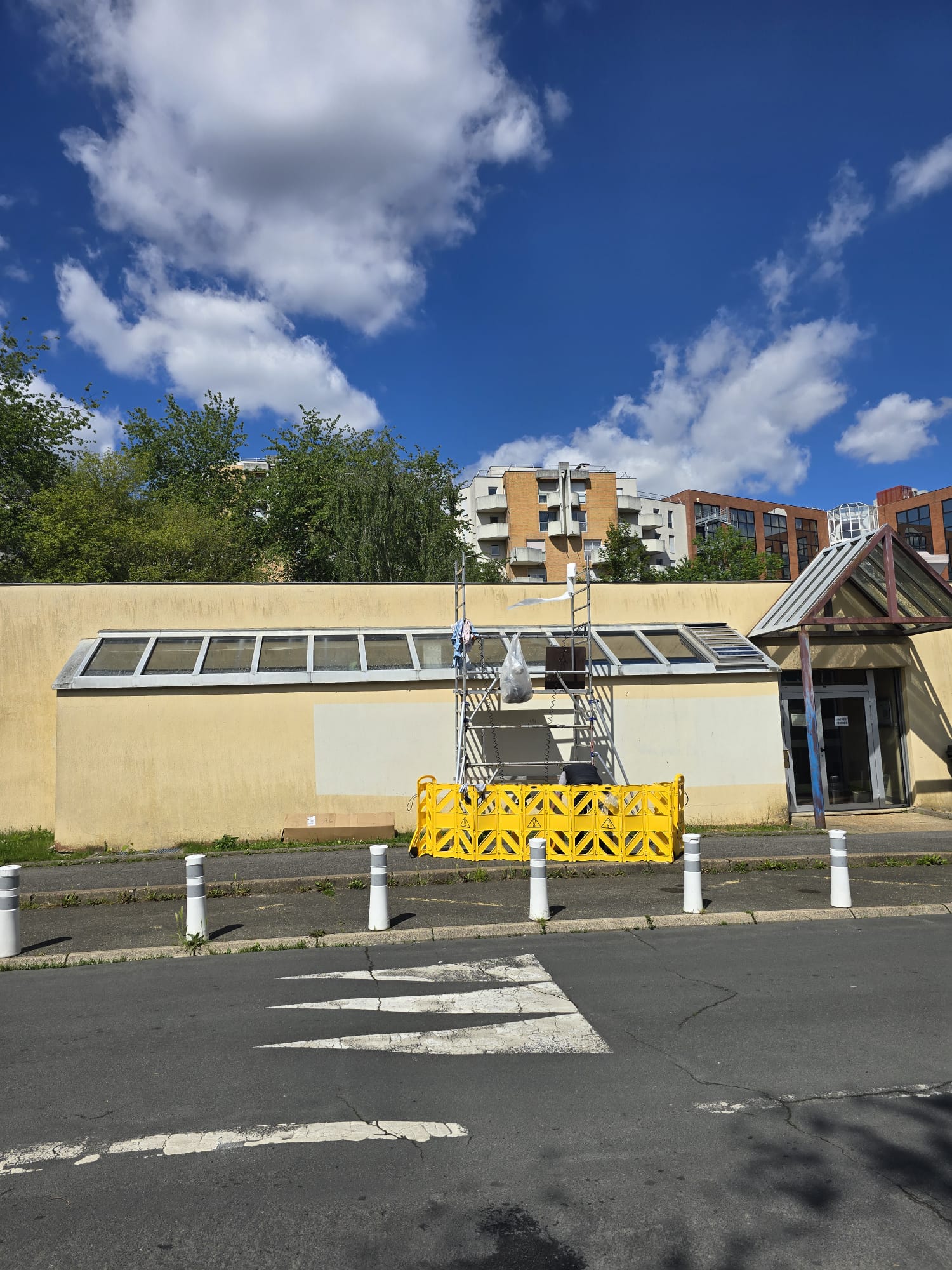 Technicien DFP France en cours de pose du film solaire sur la verrière du studio Solarscène, perché en haut de l'échafaudage de chantier