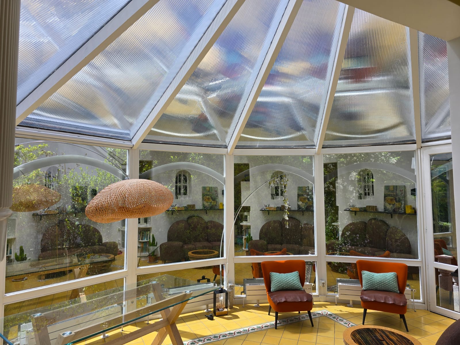 Salon sous la véranda après pose du film solaire — espace lumineux et confortable, mobilier et fauteuils visibles, plus de surchauffe