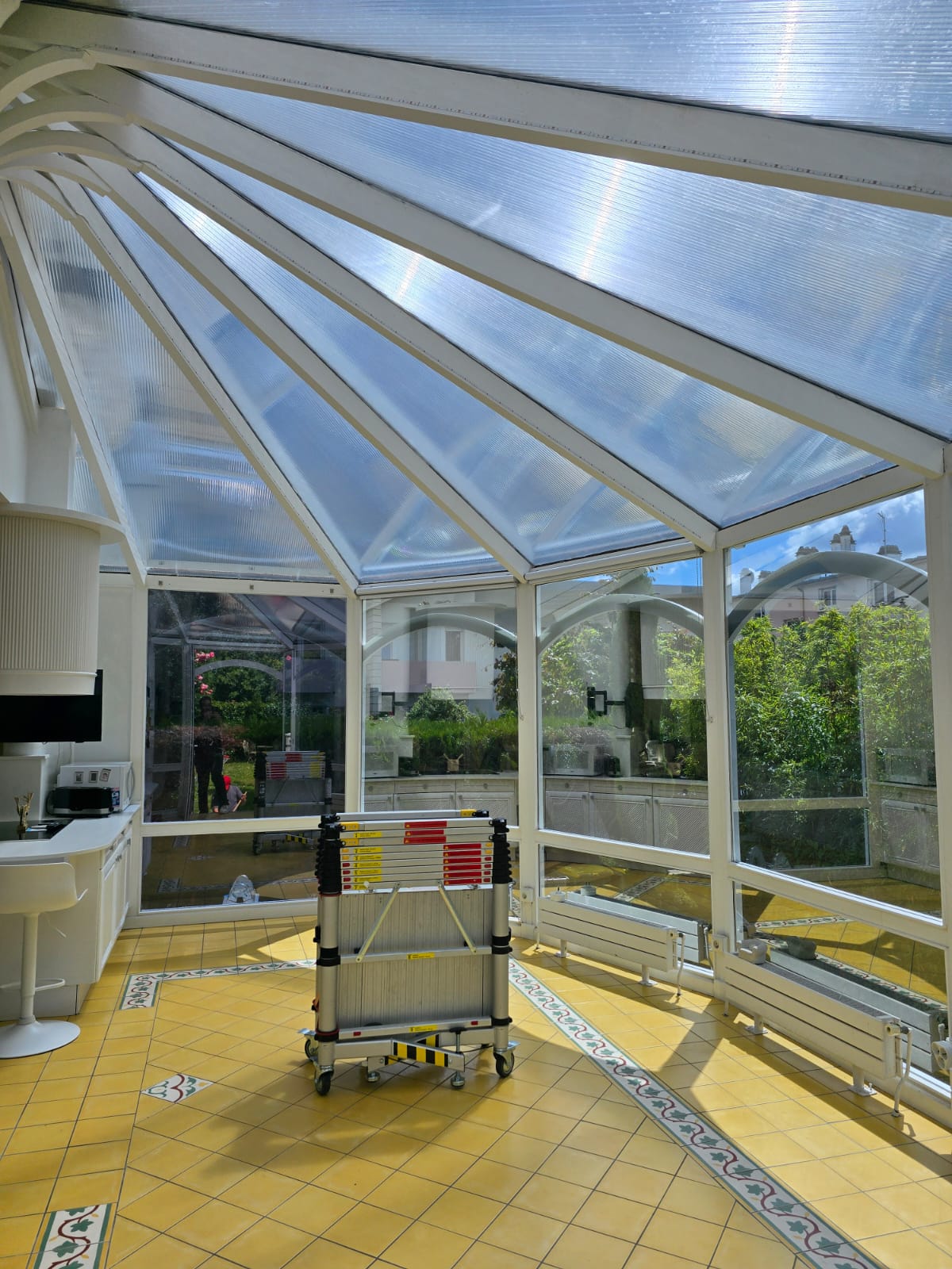 Toiture de la véranda traitée au film solaire, vue de l'intérieur — les panneaux filtrent le rayonnement tout en laissant passer la lumière du jour