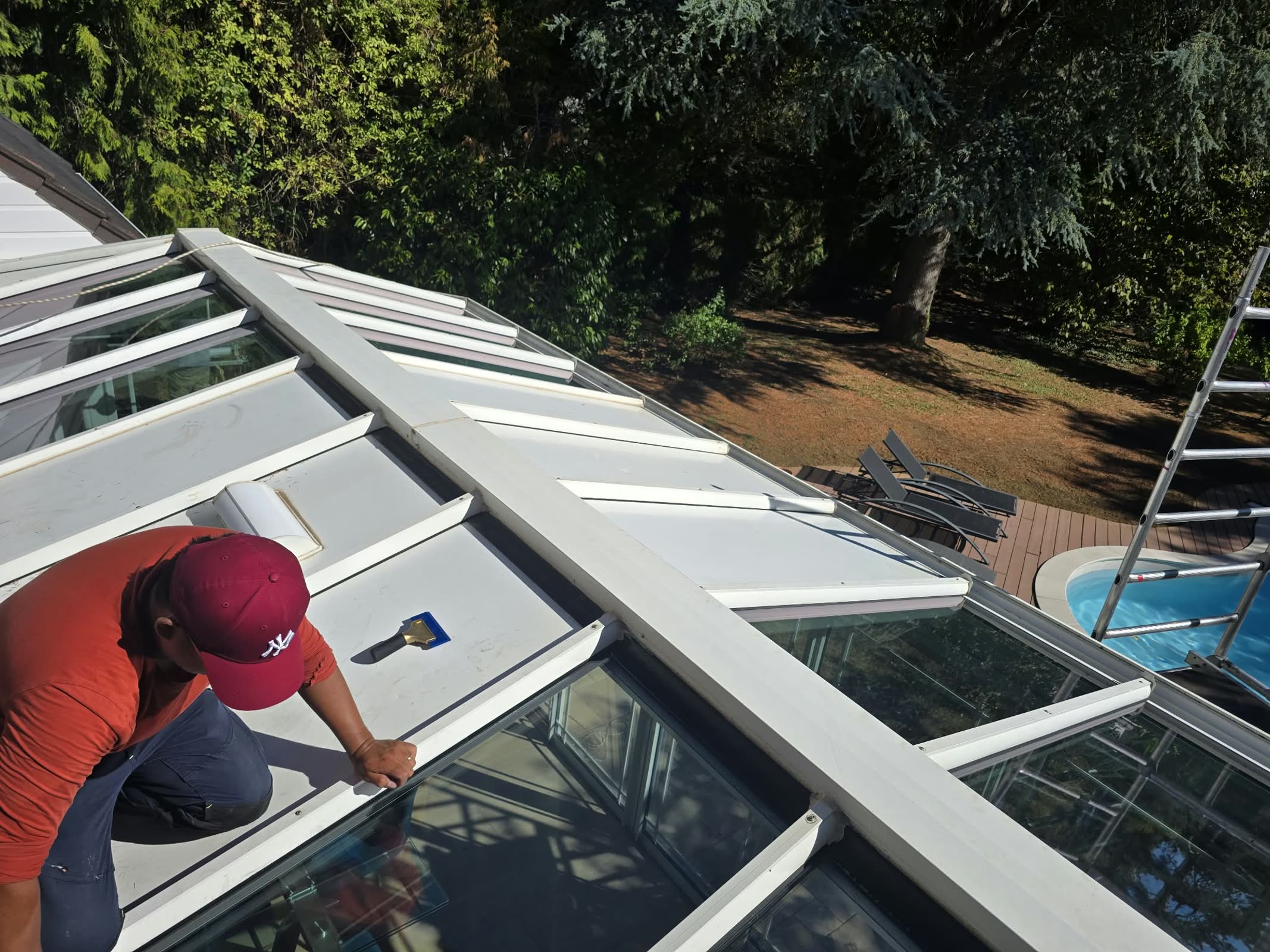 Technicien DFP France harnaché appliquant le film solaire sur un panneau de toiture de la véranda, Lésigny (77)