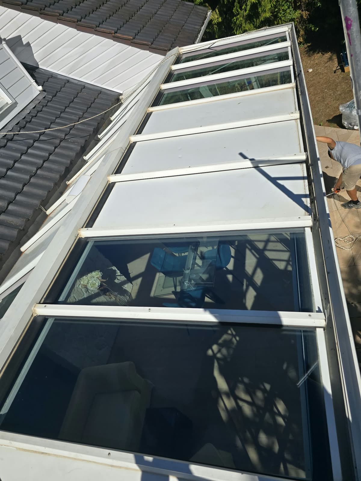 Toiture de la véranda vue depuis le toit de la maison : panneaux vitrés traités au film solaire extérieur, Lésigny (77)