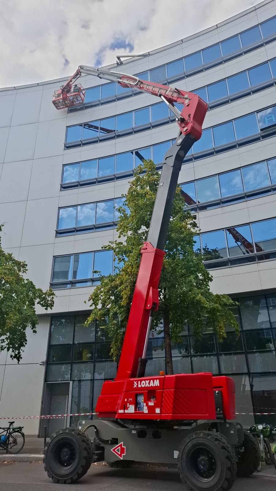 Nacelle articulée déployée depuis la rue jusqu'à la toiture d'un immeuble à Paris 14e pour l'accès de l'équipe DFP France à la verrière, zone balisée au sol